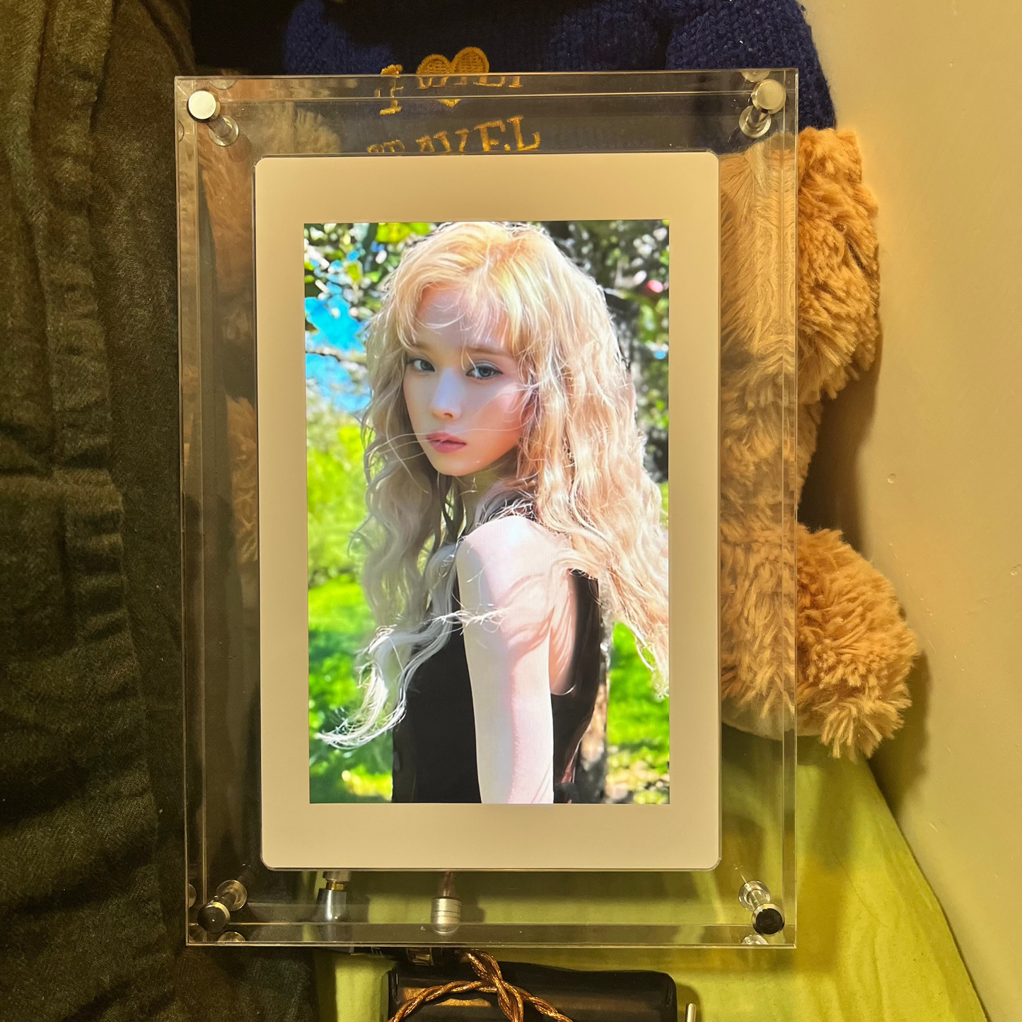 KPOPIFY Poster on a desk displaying a K-pop idol photo, styled with plushies in a fan bedroom